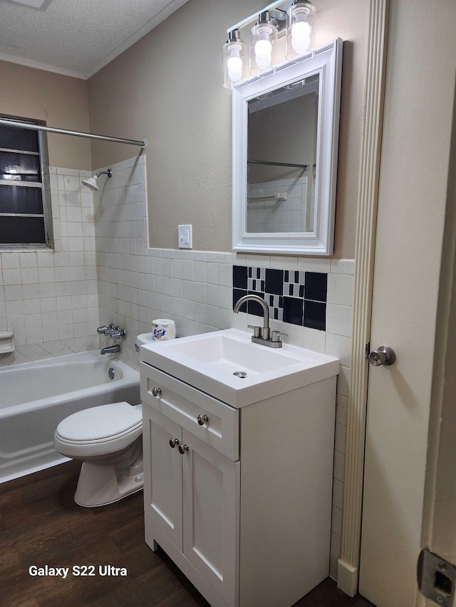 full bathroom with wood-type flooring, tile walls, vanity, toilet, and a textured ceiling