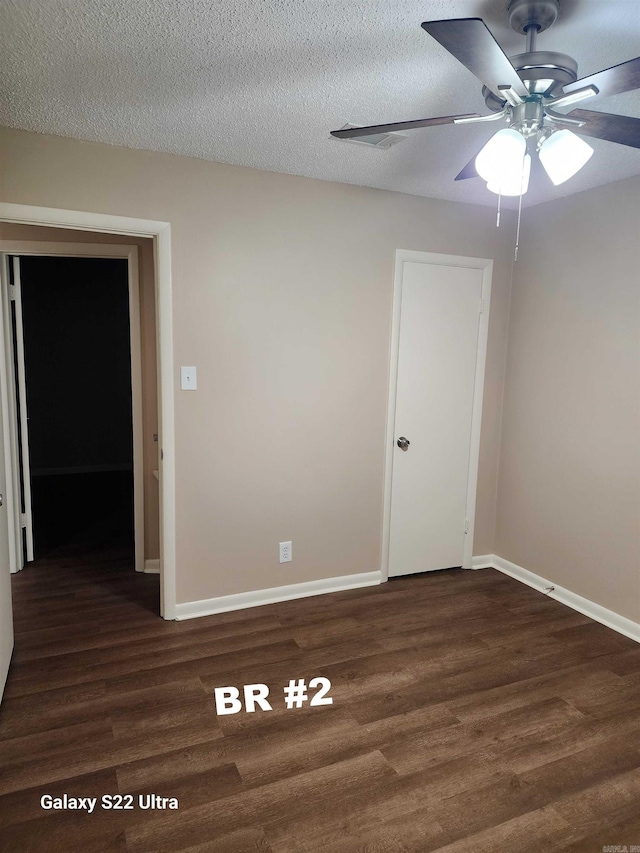 spare room with ceiling fan, dark wood-type flooring, and a textured ceiling