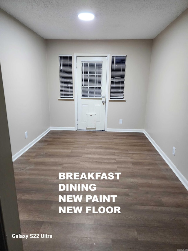 empty room with dark hardwood / wood-style flooring and a textured ceiling