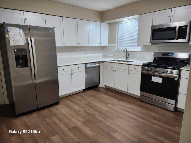 kitchen with sink, white cabinets, backsplash, stainless steel appliances, and dark wood-type flooring