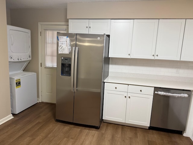 kitchen with appliances with stainless steel finishes, dark hardwood / wood-style floors, stacked washer / dryer, tasteful backsplash, and white cabinets