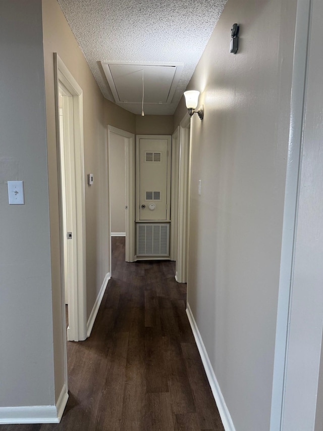 hall featuring dark wood-type flooring and a textured ceiling