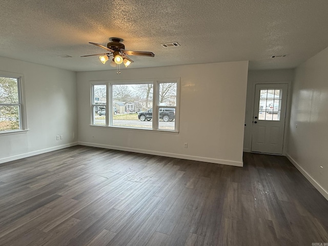 interior space with ceiling fan, a wealth of natural light, a textured ceiling, and dark hardwood / wood-style flooring