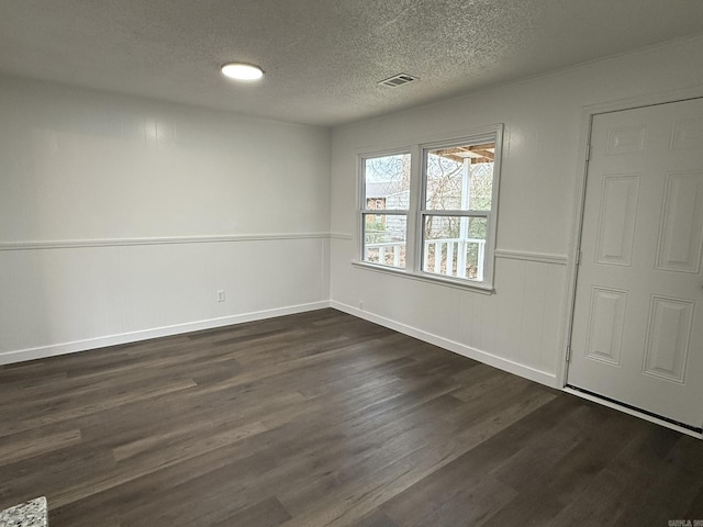 empty room with dark hardwood / wood-style floors and a textured ceiling