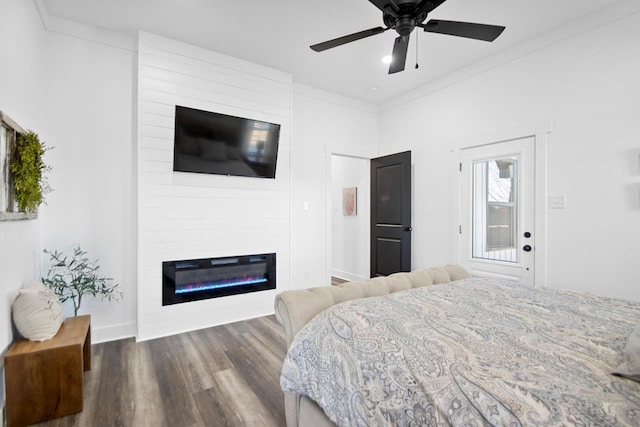 bedroom with ceiling fan, crown molding, a fireplace, and wood-type flooring