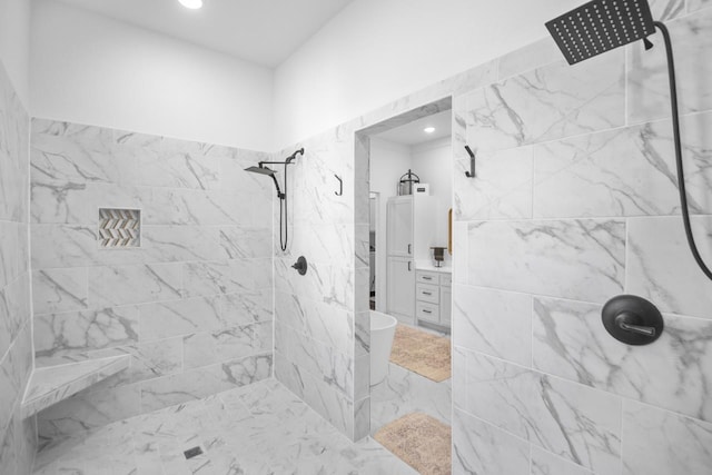 bathroom with a tile shower and vanity