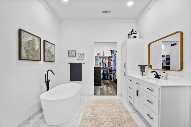 bathroom with crown molding, vanity, and a bath