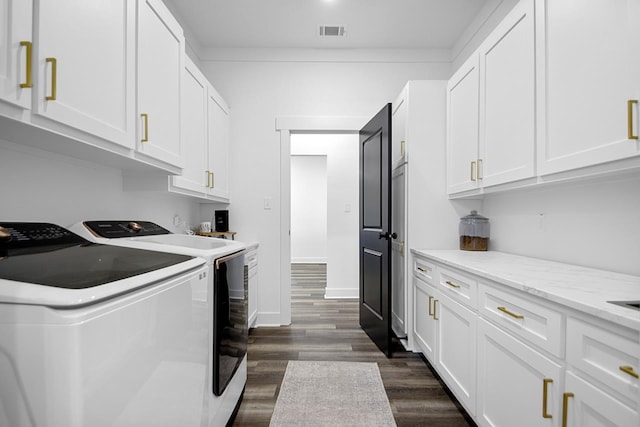 laundry room featuring separate washer and dryer, dark hardwood / wood-style floors, and cabinets