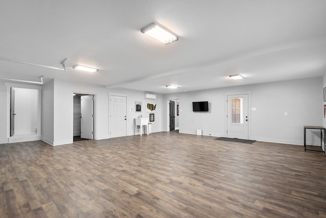 interior space with dark wood-type flooring and a wall unit AC