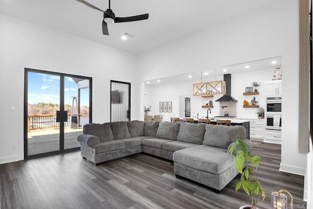 living room featuring dark wood-type flooring, a towering ceiling, crown molding, and sink