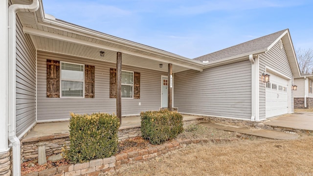 view of exterior entry with a garage and a porch