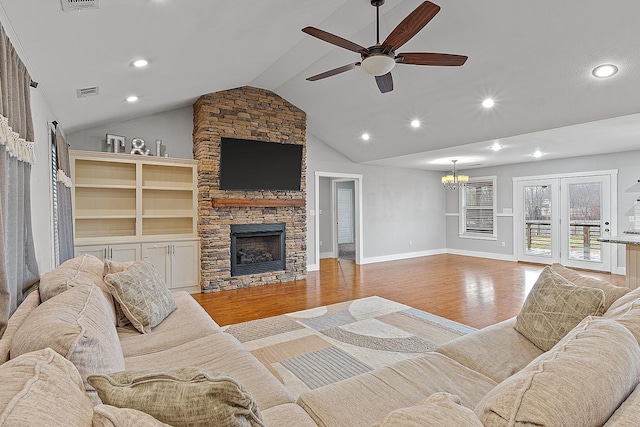 living room featuring high vaulted ceiling, ceiling fan with notable chandelier, a fireplace, and light hardwood / wood-style flooring