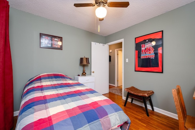 bedroom featuring ceiling fan, wood-type flooring, and a textured ceiling