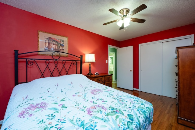 bedroom with ceiling fan, dark hardwood / wood-style floors, a closet, and a textured ceiling