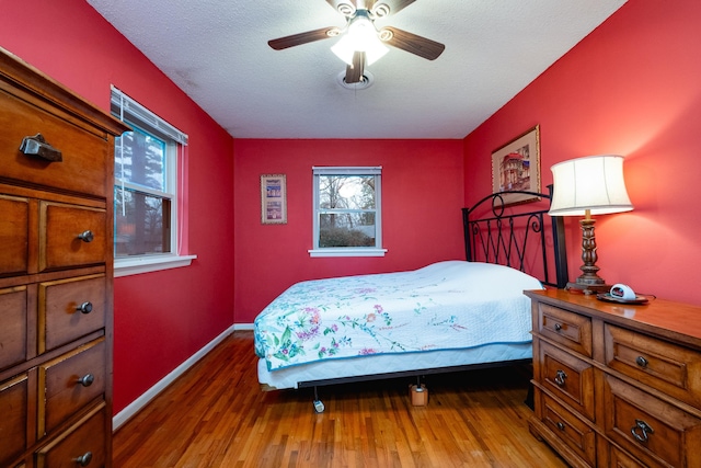 bedroom with ceiling fan, hardwood / wood-style flooring, and a textured ceiling