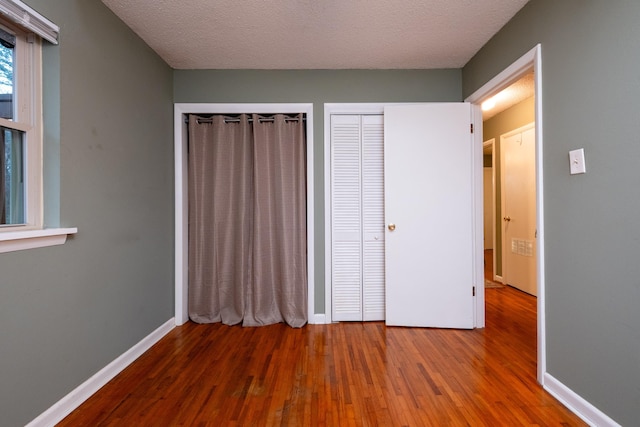 unfurnished bedroom featuring hardwood / wood-style floors, a closet, and a textured ceiling