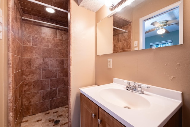 bathroom with vanity, a tile shower, and ceiling fan