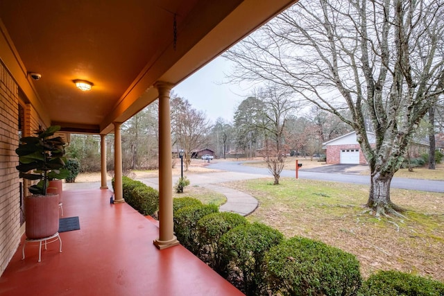 view of patio / terrace with a garage, an outdoor structure, and a porch