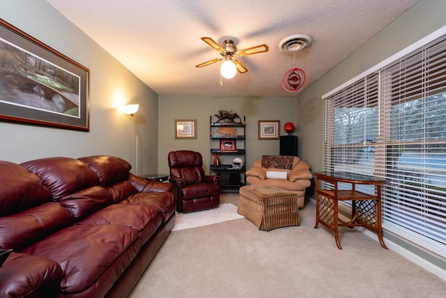 living room featuring ceiling fan, light colored carpet, and a textured ceiling