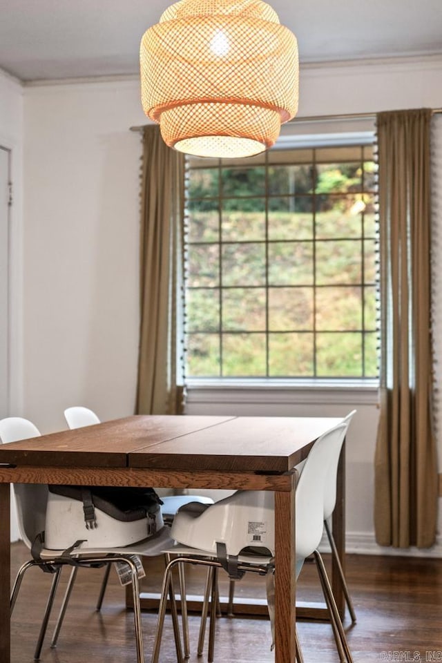 dining area with crown molding and dark wood-type flooring