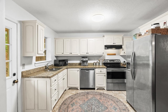 kitchen with sink, white cabinetry, a textured ceiling, appliances with stainless steel finishes, and dark stone counters