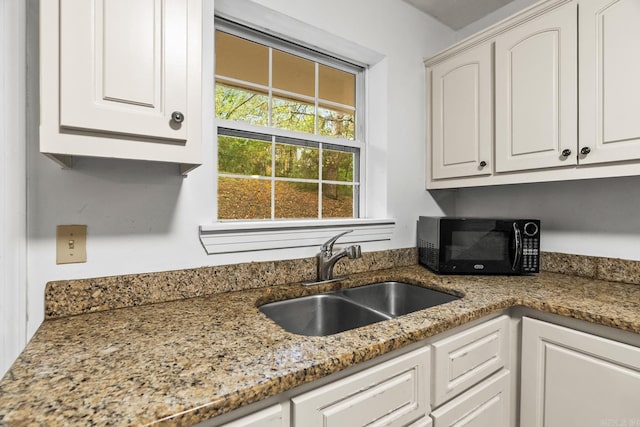 kitchen featuring white cabinetry, sink, and light stone countertops