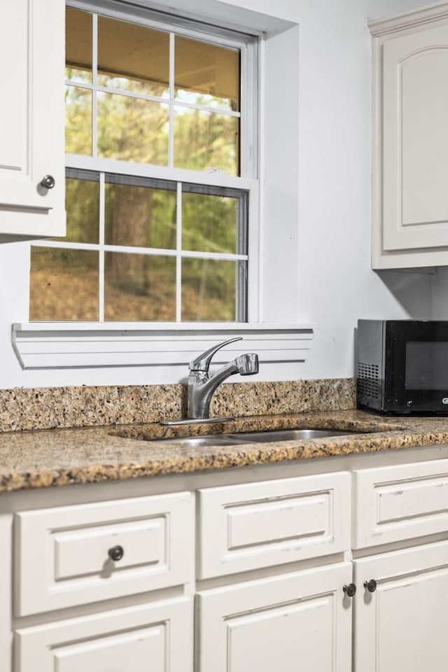 interior space with white cabinetry, sink, and dark stone countertops