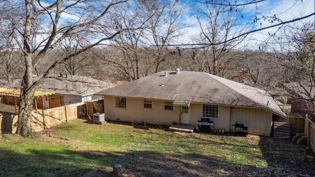 rear view of house featuring central AC unit and a yard