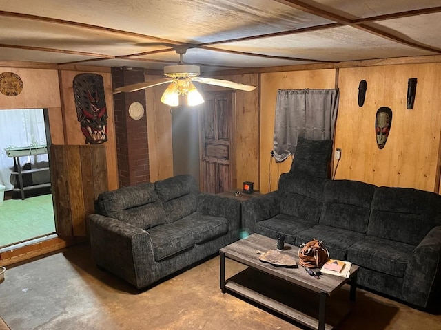 living room featuring ceiling fan, concrete floors, and wood walls