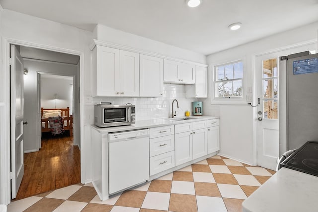 kitchen with appliances with stainless steel finishes, sink, decorative backsplash, and white cabinets