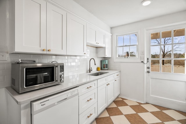 kitchen with white dishwasher, sink, and white cabinetry