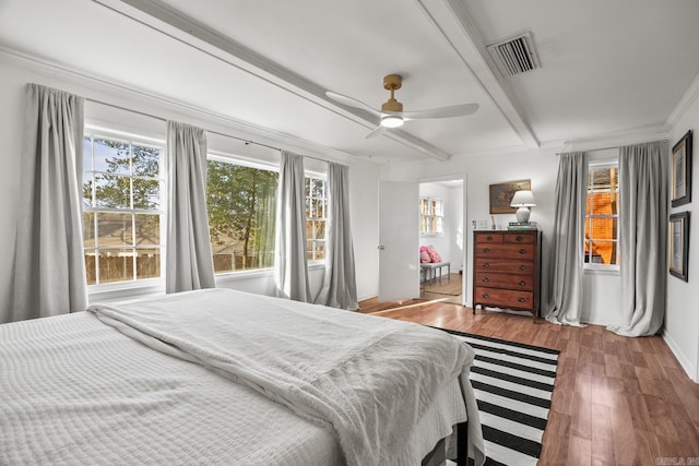 bedroom with beam ceiling, wood-type flooring, ornamental molding, and ceiling fan