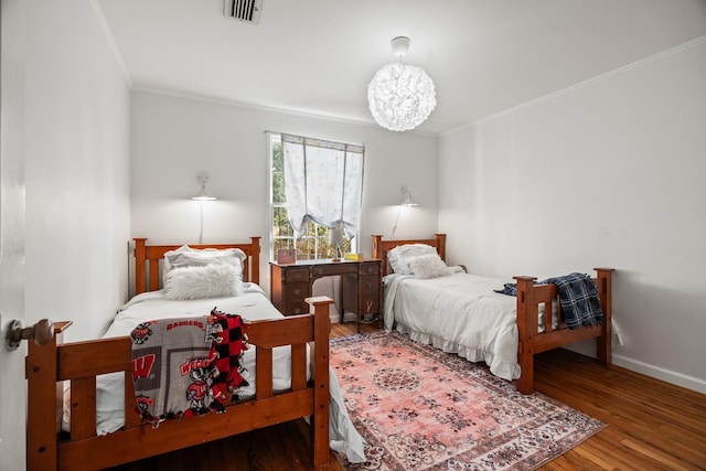 bedroom with hardwood / wood-style flooring, ornamental molding, and a notable chandelier