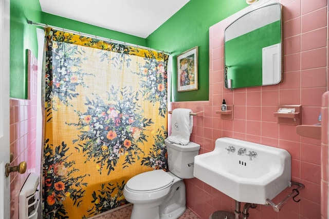 bathroom with a shower with shower curtain, toilet, sink, and tile walls