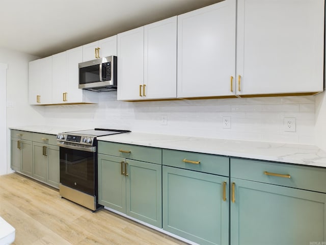 kitchen with backsplash, stainless steel appliances, light hardwood / wood-style flooring, and white cabinets