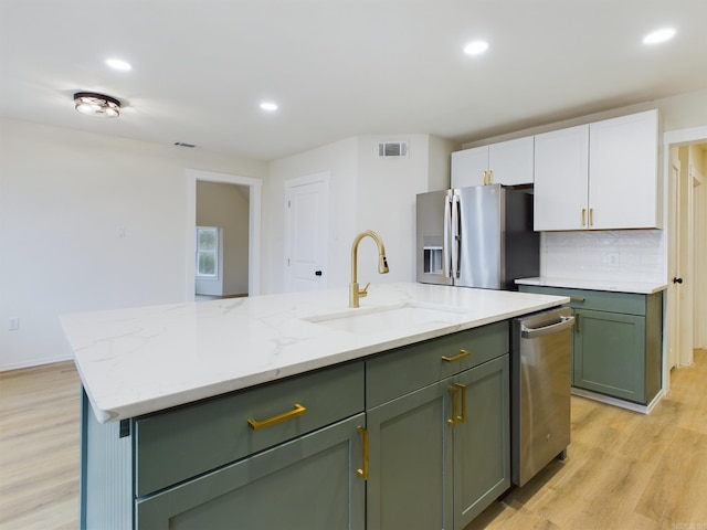 kitchen with sink, green cabinets, white cabinetry, stainless steel appliances, and an island with sink