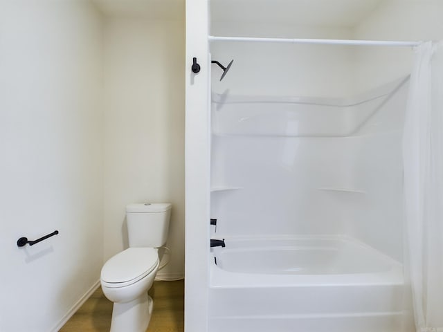 bathroom featuring hardwood / wood-style flooring, toilet, and washtub / shower combination