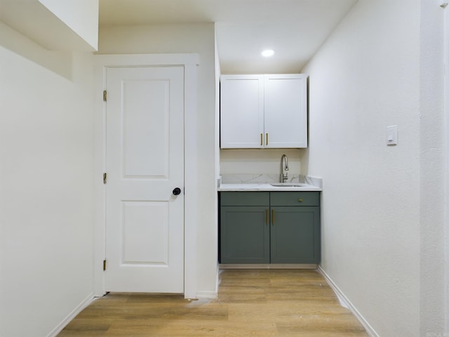 bar featuring sink, white cabinets, and light hardwood / wood-style flooring