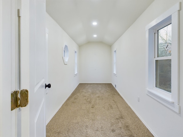 spare room featuring light colored carpet and lofted ceiling