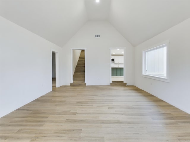 unfurnished living room featuring high vaulted ceiling and light wood-type flooring