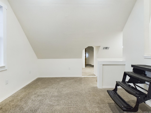 interior space with vaulted ceiling and light carpet