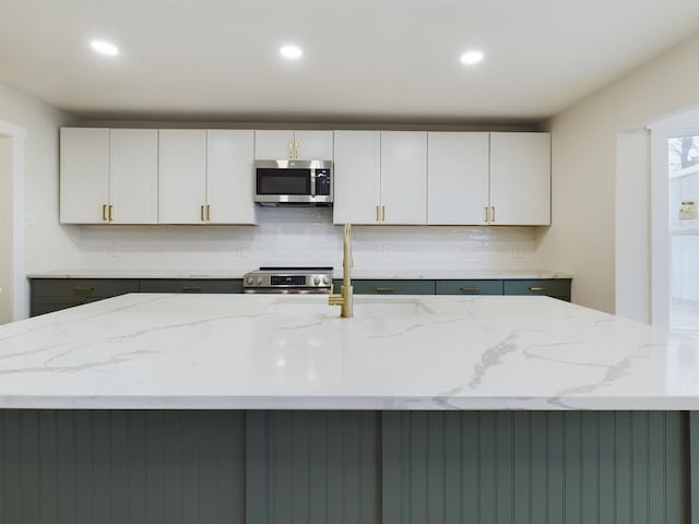 kitchen with white cabinetry, appliances with stainless steel finishes, and a kitchen island with sink