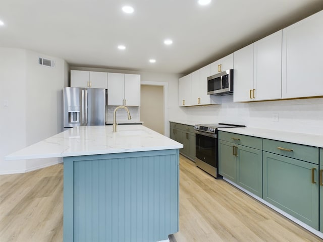 kitchen featuring a kitchen island with sink, sink, white cabinetry, and appliances with stainless steel finishes