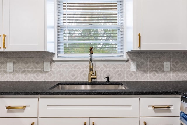 kitchen featuring white cabinetry, sink, and tasteful backsplash