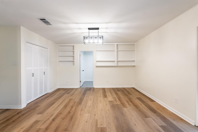 unfurnished room with built in features and light wood-type flooring