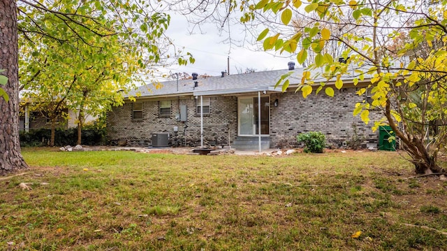 back of house with central AC unit and a lawn