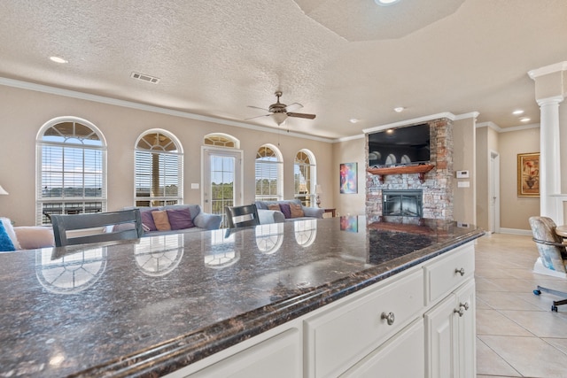 kitchen with dark stone counters, a wealth of natural light, light tile patterned floors, and white cabinets