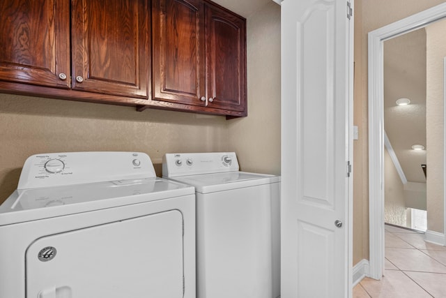 washroom featuring cabinets, washing machine and dryer, and light tile patterned flooring