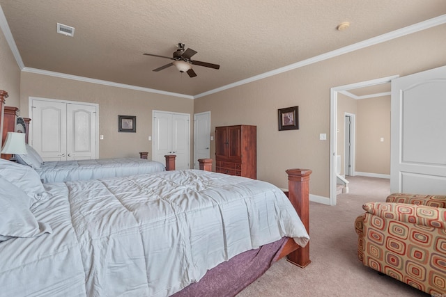 bedroom featuring ceiling fan, multiple closets, crown molding, light carpet, and a textured ceiling