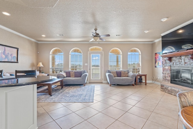 living room featuring a stone fireplace, ornamental molding, a textured ceiling, and light tile patterned flooring